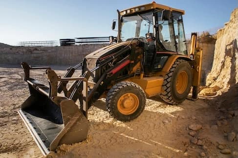 Heavy excavator equipment working on construction site with operator in safety gear